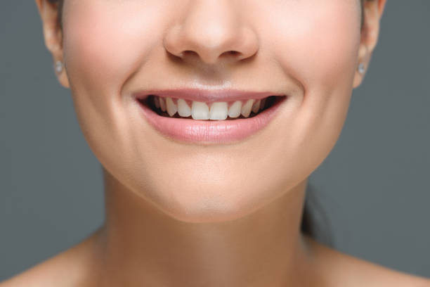 istock partial view of smiling woman with beautiful white teeth isolated on grey 1027690706