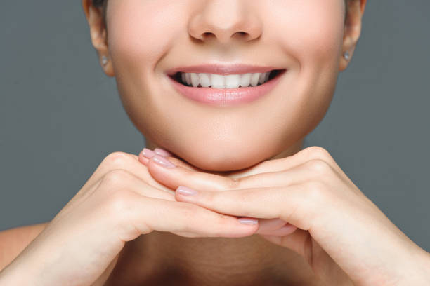 istock partial view of smiling woman with white teeth isolated on grey 1027690726