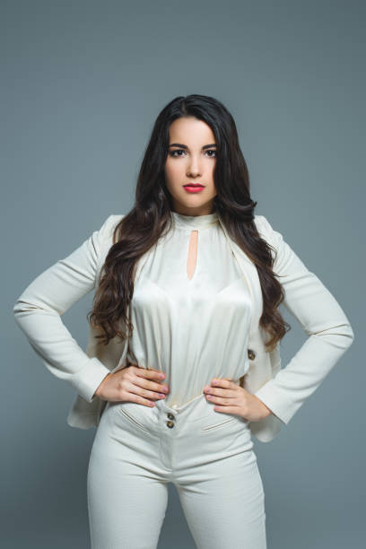 istock beautiful brunette woman posing in white elegant suit, isolated on grey 1027693524