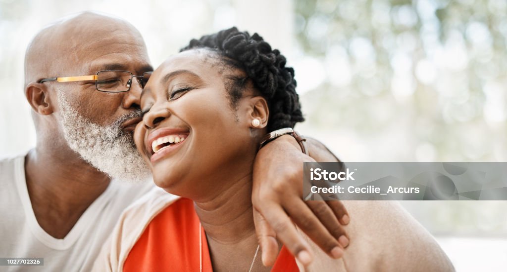 The greatest gift I ever got was you Shot of a mature man affectionately kissing his wife at home African-American Ethnicity Stock Photo