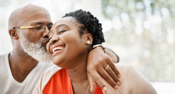 The greatest gift I ever got was you Shot of a mature man affectionately kissing his wife at home african american ethnicity stock pictures, royalty-free photos & images