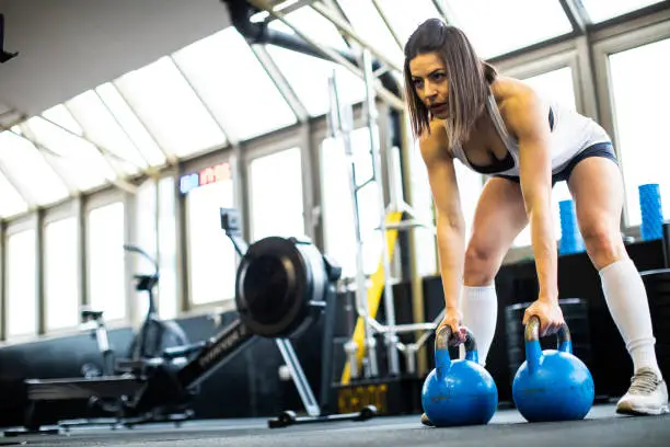 Young woman exercising with kettlebells in the gym