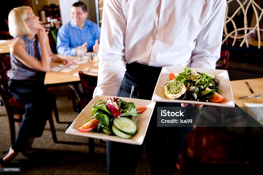 Vista ritagliata di Cameriere holding Insalata piatti al ristorante - Foto stock royalty-free di Cibo