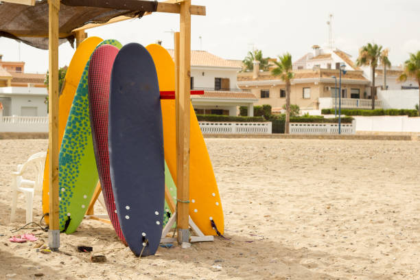 Several surfboards of different colors placed on a wooden structure for storage