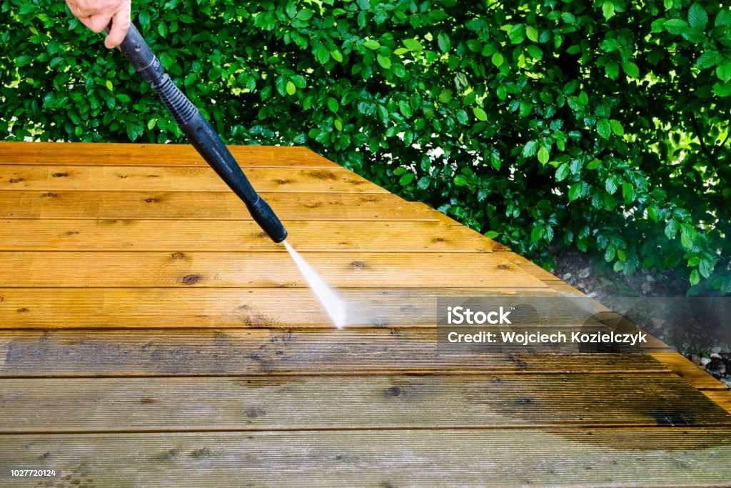 cleaning terrace with a power washer - high water pressure cleaner on wooden terrace surface Washing Stock Photo