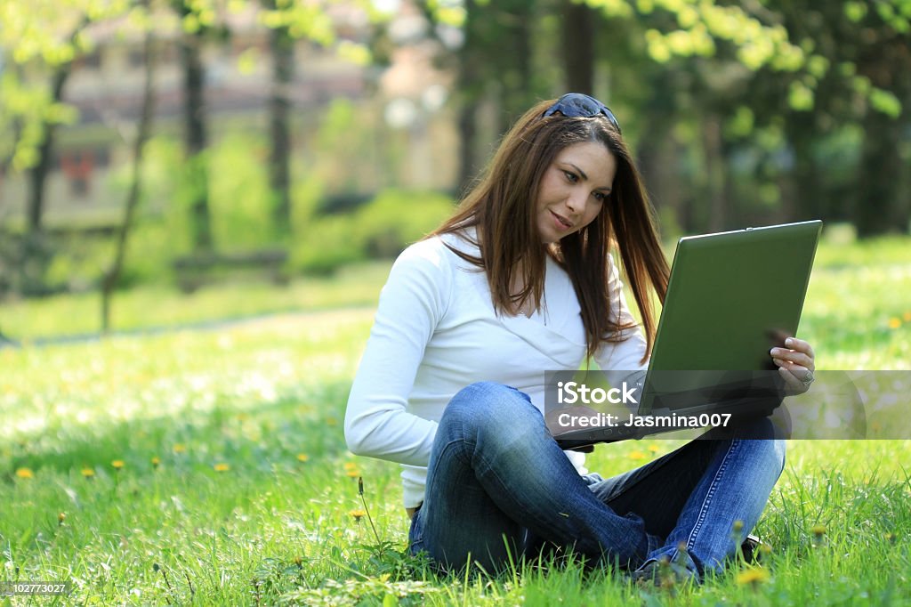 Mujer joven con ordenador portátil en el parque - Foto de stock de 20 a 29 años libre de derechos