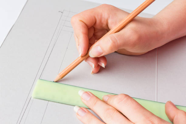 istock woman hands with long nails drawn projects with pencil and ruler on a white paper, mockups close-up 1027731034