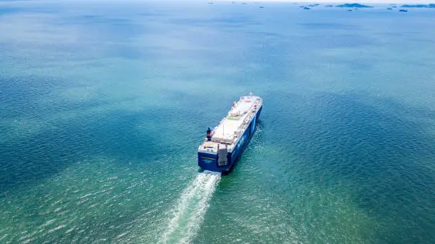 Photo of Cargo ship carries the container heading to the port where is many cranes at the edge. It is the important part of imported and exported economy.