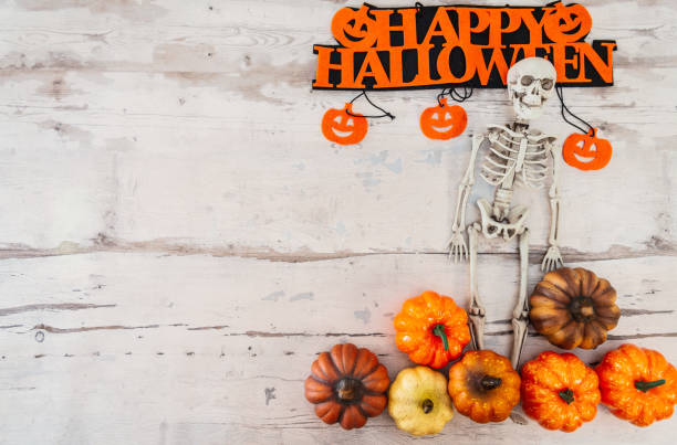 istock Halloween concept with a pumpkin and skeleton on background 1027739204