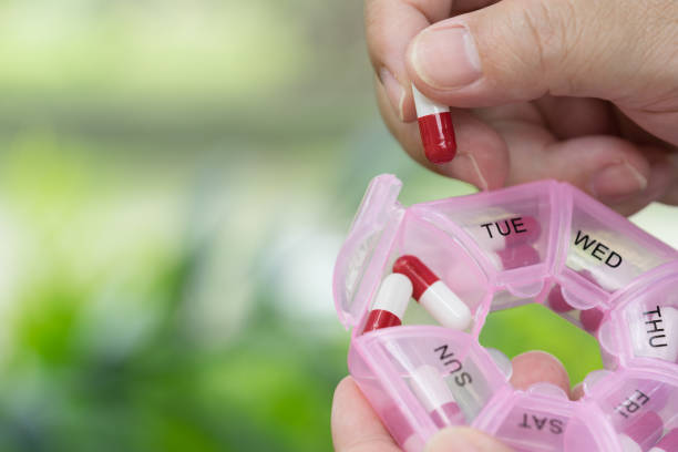 Hand picking up capsule tablet from plastic pill box. Health care and medical concept. stock photo