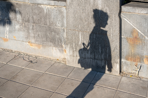 Shadow of a girl with a bag  on the fence