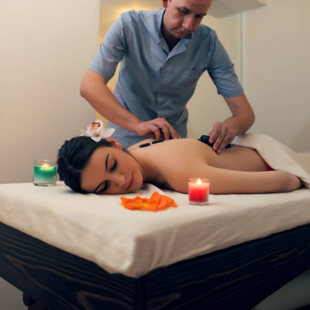 frau mit hot-stone-massage im spa-salon - lastone therapy recovery zen like stone stock-fotos und bilder