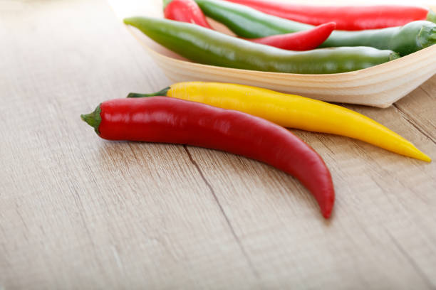 colored chili peppers on a wooden surface