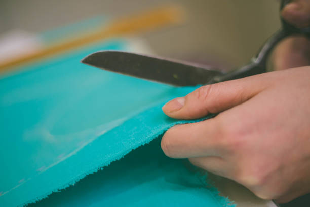 istock Seamstress is cutting drawing for a dress with scissors. Style and design development and creating garment, clothes sew and repair service, seamstress at work concept 1027771544
