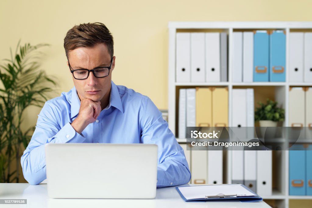 Entreprneur checking e-mails Pensive young entreprneur checking e-mails on his laptop Adult Stock Photo