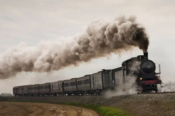 Vintage black steam train running on rails in a foggy day