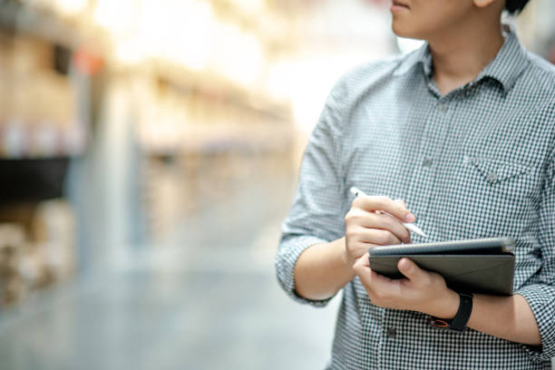 young asian man worker doing stocktaking of product in cardboard box on shelves in warehouse by using digital tablet and pen. physical inventory count concept - asian ethnicity shopping mall supermarket store imagens e fotografias de stock