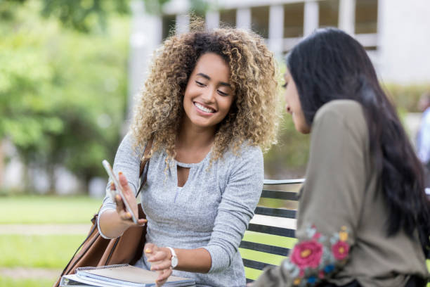 istock College student shows friend something on smartphone 1027807562