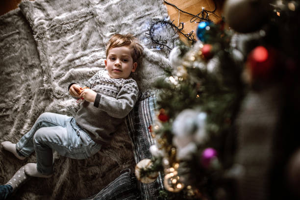 istock Boy laying under Christmas tree and playing with ornaments 1027823156