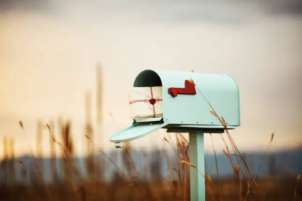 Pastel teal mailbox with stack of love letters, with heart seal