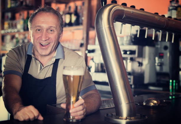 istock Adult barman is giving beer with foam to client 1027848430
