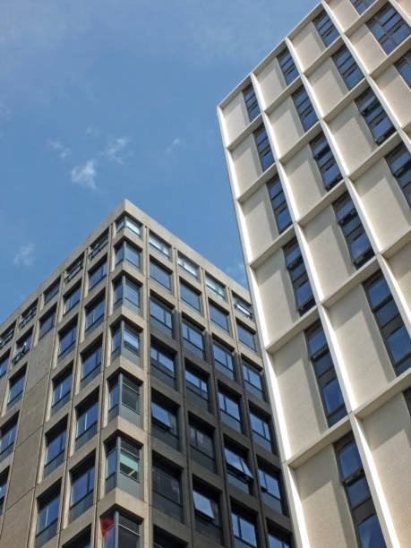 istock vertical view of a white high white concrete buildings with sunlight and blue sunny sky reflected in the windows 1027850792