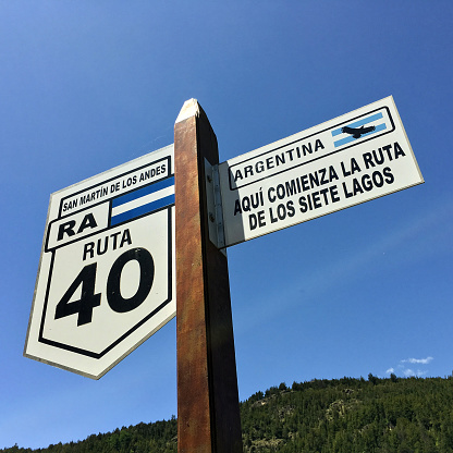 San Martin de los Andes, Argentina - December 4, 2017: Wooden pole with signs indicating the starting point within route 40 of the Seven Lakes Road, a very famous section of the highway passing through magnificent lakes in the area