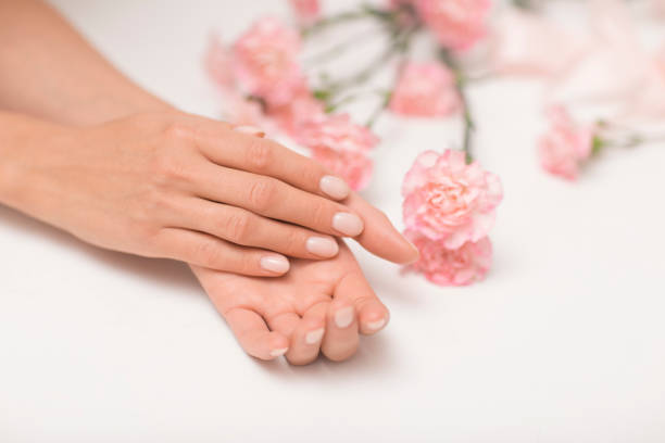 istock Manicure. Beautiful and delicate hands on white background with pink flowers. 1027864002