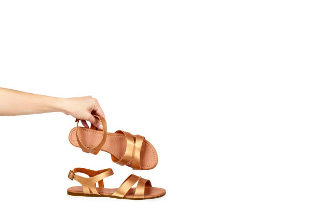 istock Golden color eco leather sandals with hand isolated on white background, copy space template 1027868052