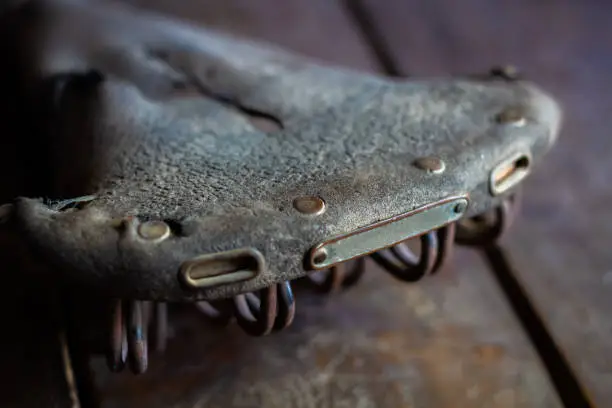 old style worn dry bicycle saddle on wooden surface