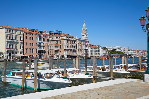 Venice, Grand Canal view with motorboats taxi, buildings an Saint Mark bell tower in a sunny day in Italy