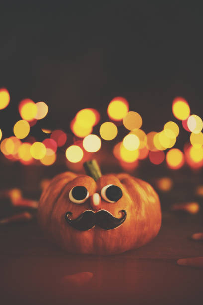 istock Cute pumpkin hipster character with handmade expression and holiday lights 1027885996