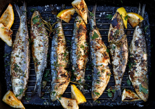sardinhas assadas em uma marinada de limão ervas sobre uma chapa de grelhar. grelhados, churrasqueira - gastronomia de portugal - fotografias e filmes do acervo