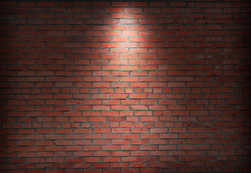 abstract old brick wall in the dark with spotlight warm light tone. brick wall in empty room. brick wall background for wallpaper