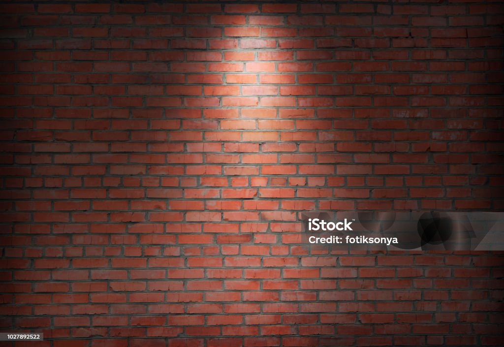 abstract old brick wall in the dark with spotlight warm light tone. abstract old brick wall in the dark with spotlight warm light tone. brick wall in empty room. brick wall background for wallpaper Brick Wall Stock Photo