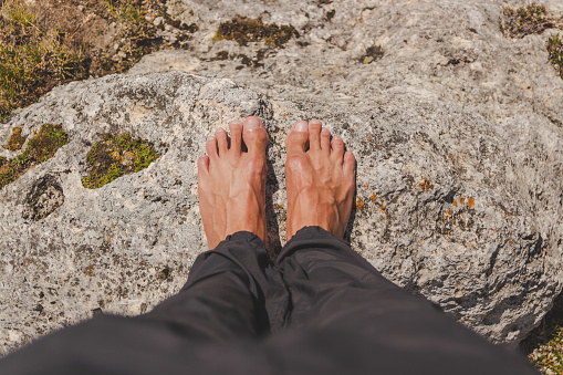 nude feet of a boy standing parallel on a white rock