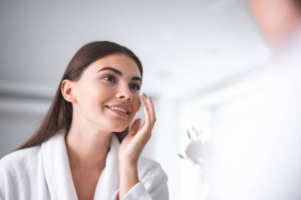 istock Satisfied woman applying cream on face indoor 1027900790