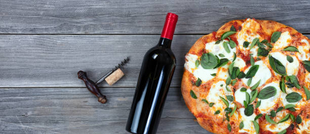Freshly cooked homemade tomato and cheese pizza and red wine ready to serve stock photo