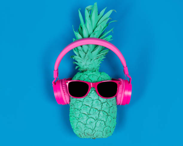 istock Pineapple in pink headphones and glasses on a blue background 1027903280