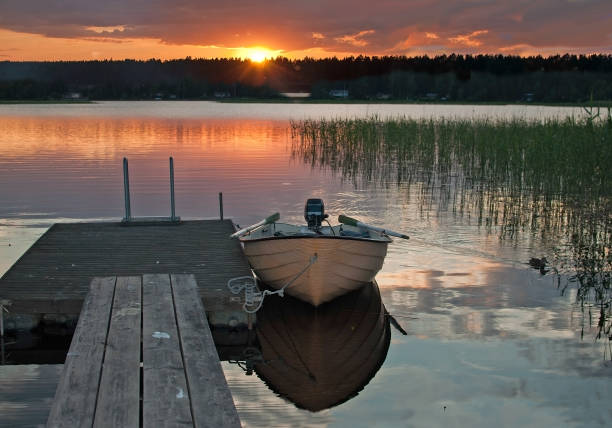istock Small boat moored by wooden jetty at sunset 1027916824