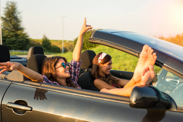 istock Two gorgeous young women enjoying a car ride in a convertible while smiling 1027921294