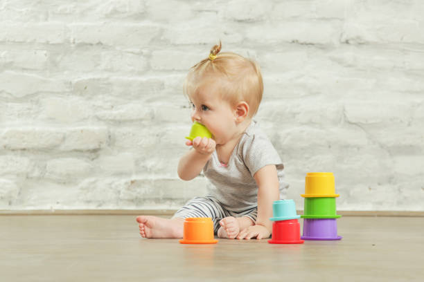 bambina che gioca sul pavimento con tazze educative in plastica, concetto di apprendimento precoce - baby cup foto e immagini stock