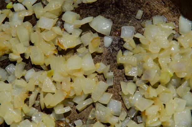 Diced onions frying in an iron pan up close