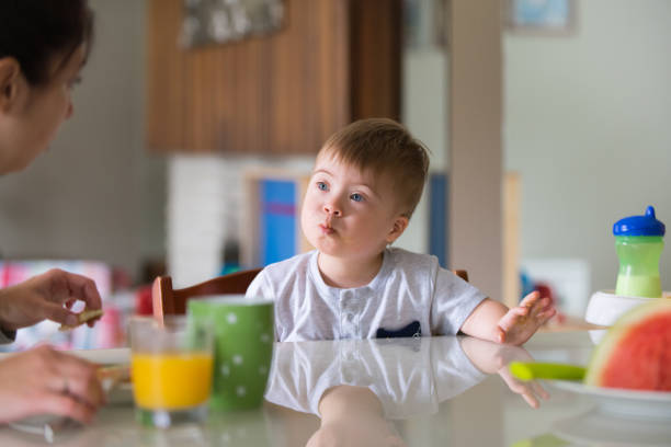 istock Down's Syndrome sweet boy eating breakfast with his mother 1027930192