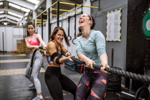 battle rope workout on cross training - gym women inside of exercising imagens e fotografias de stock