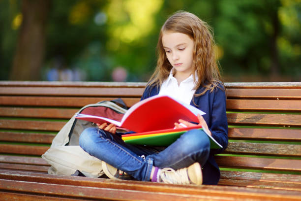 istock Adorable little schoolgirl studying outdoors on bright autumn day. Young student doing her homework. Education for small kids. 1027941042
