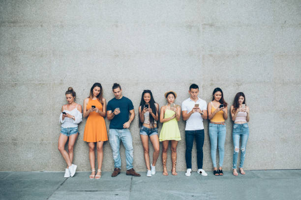 istock Young people leaning back on gray wall and social networking 1027941334