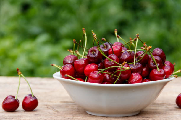 istock Bowl with fresh cherry on rustic wooden table outdoor 1027948560