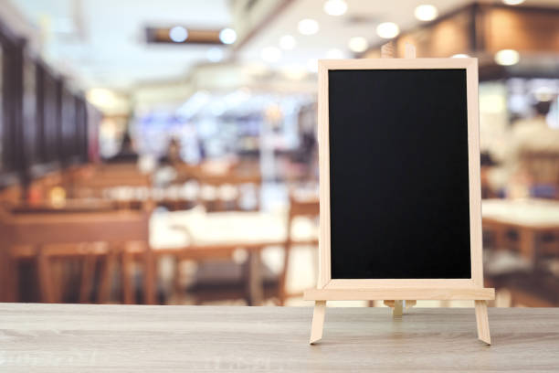 istock Blank chalkboard standing on table over blur cafe with bokeh background, space for text, mock up, product display montage 1027951226