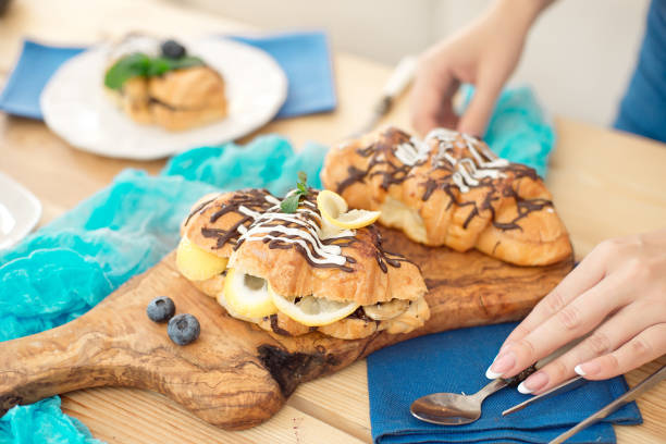 istock Close-up Female hands decorating sweet croissant on cooking table. 1027953774